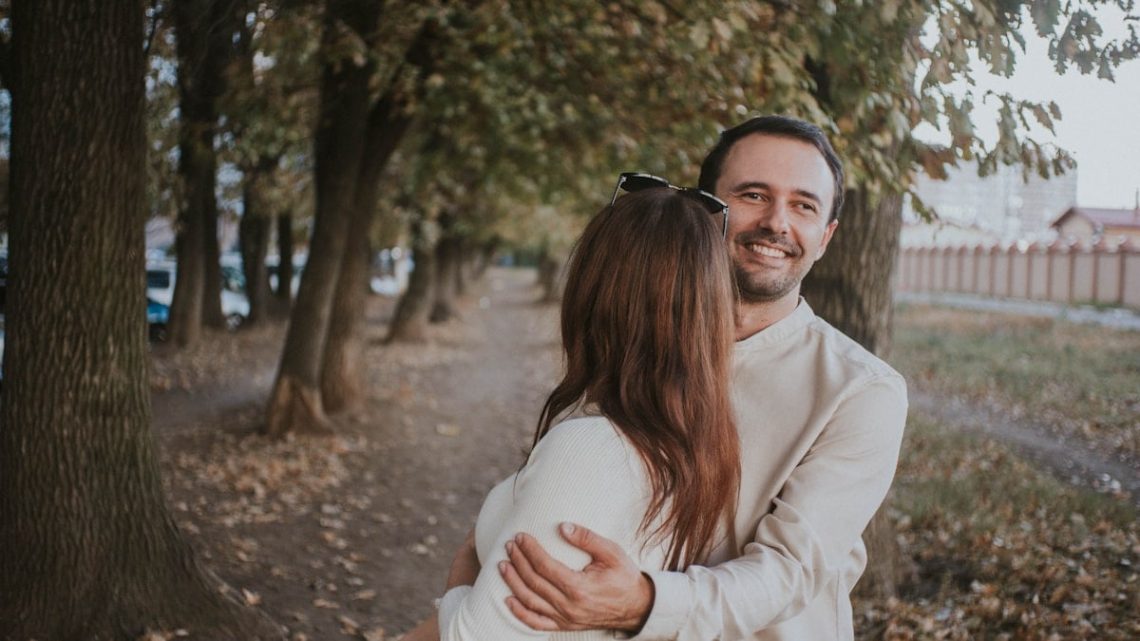 a man holding a woman in his arms in a park